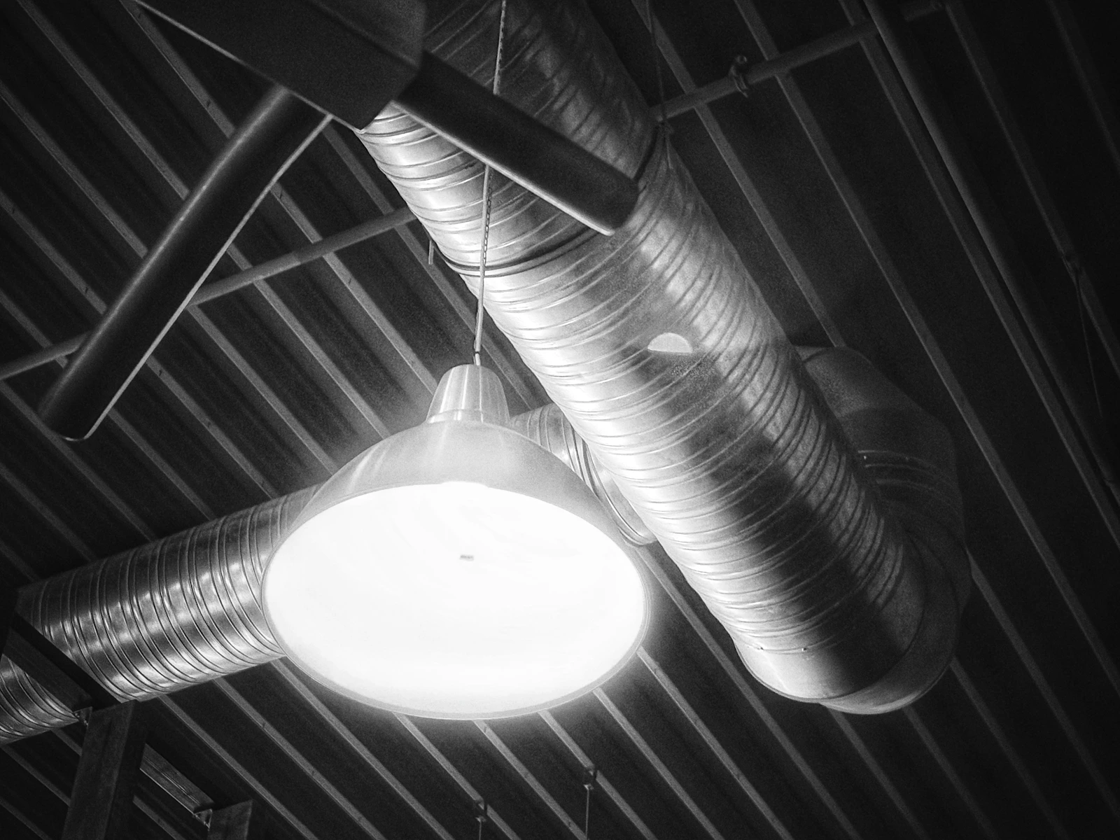 Dutos metálicos de ventilação aparentes em uma instalação predial. Fotografia ilustrativa.